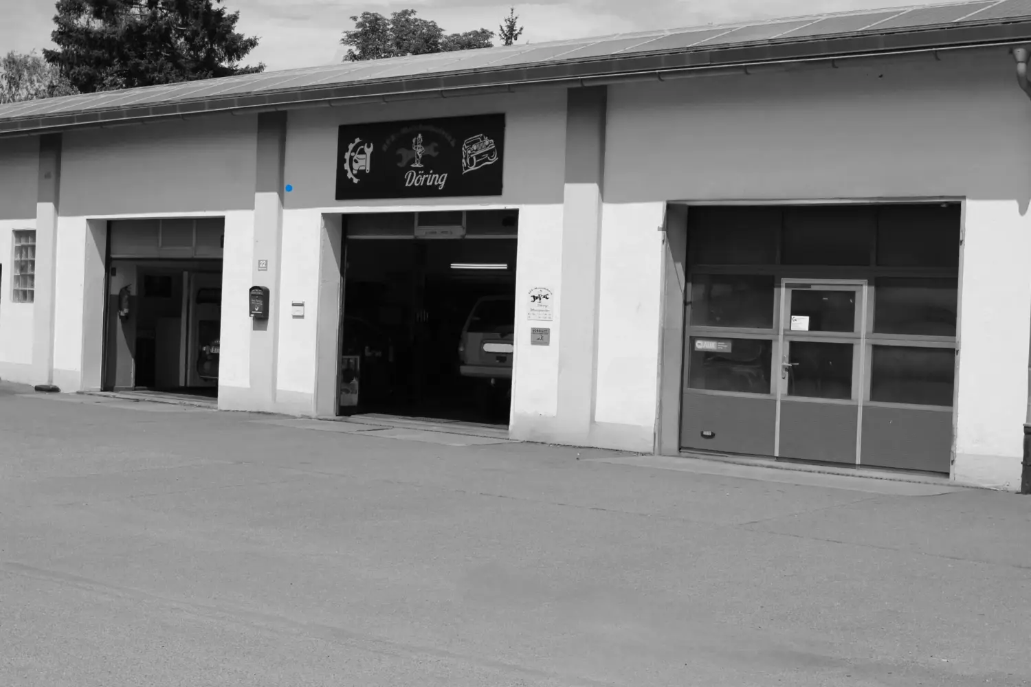Kfz Döring - Automobil Reparatur, Wartung oder Inspektion - Außenansicht der Kfz-Reparaturwerkstatt „Kfz.-Rep. Werkstatt Döring Meisterbetrieb“ mit geöffnetem Mittelgaragentor, das ein Fahrzeug im Inneren zeigt.